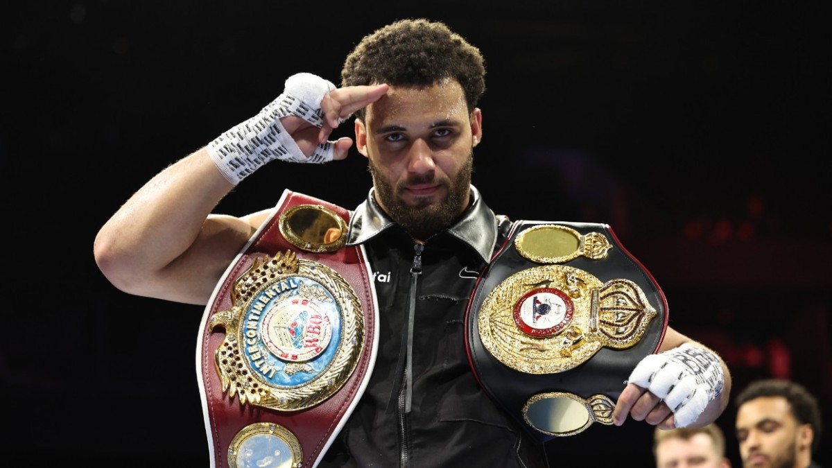 Moses Itauma salutes the crowd after knocking out Jermaine Franklin while holding his championship belts in Manchester
