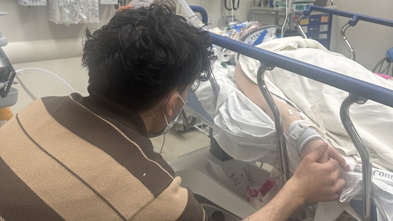 Boyfriend Jesse holds boxer Isis Sio’s hand beside her hospital bed during recovery from a medically induced coma