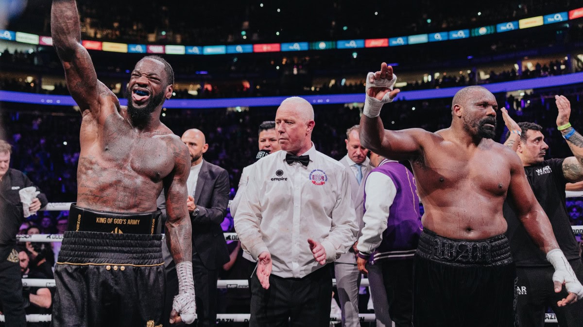 Deontay Wilder celebrates victory over Derek Chisora as referee Mark Bates stands between the fighters at the O2 Arena in London