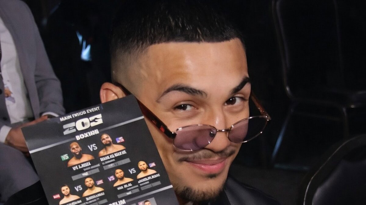 Teofimo Lopez holding a Zuffa Boxing fight card while wearing sunglasses at a media event