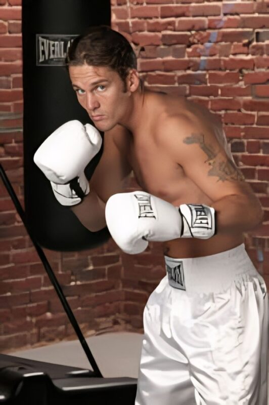 Jimmy Lange posant avec des gants de boxe Everlast blancs et un short contre un mur de briques pour la saison 1 de The Contender
